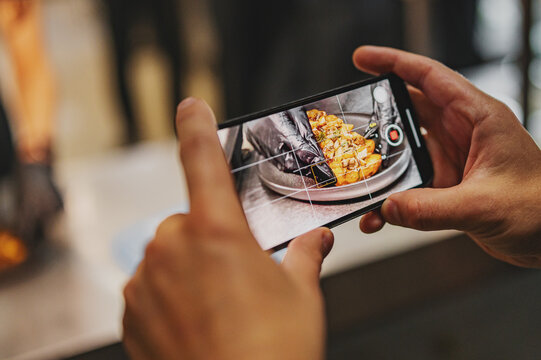 man hand with smartphone photographing food at kitchen