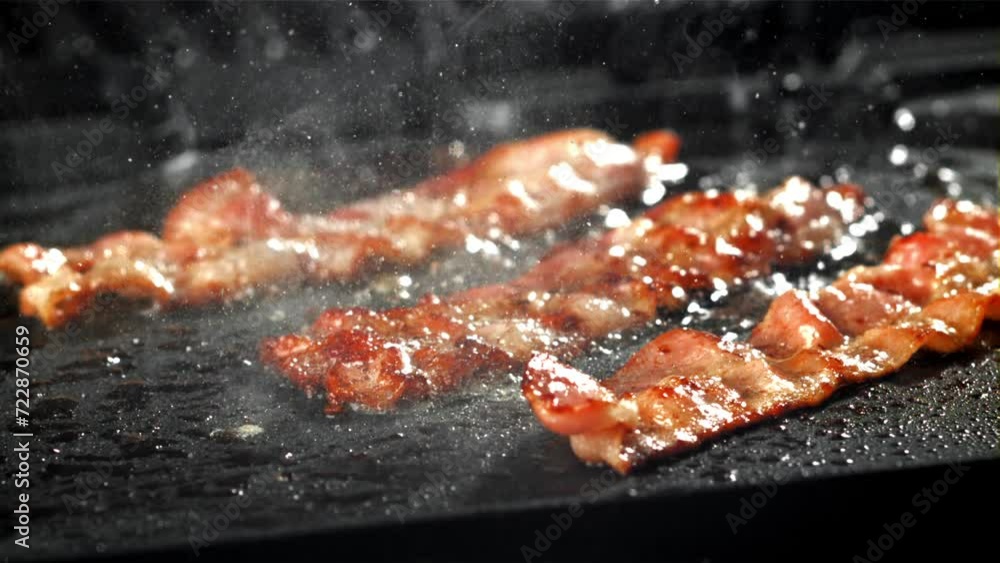 Sticker The bacon is fried in a pan with a splash of oil. Filmed on a high-speed camera at 1000 fps. High quality FullHD footage