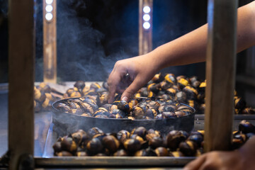 Close-up of the chestnut seller's hand roasting chestnuts outdoors on Istiklal Street