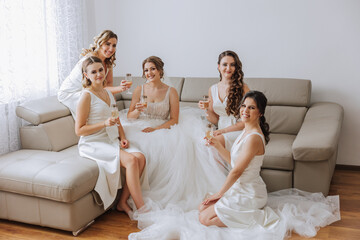 Photo bride with her friends drinking champagne from glasses. Cropped shot of a beautiful young...