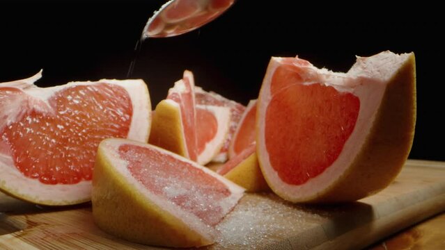 I sprinkle sugar on a grapefruit wedge, the camera slowly moves forward. Slow-motion close-up.