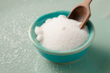 Granulated white sugar in a turquoise bowl. Close-up. Front view from low angle.