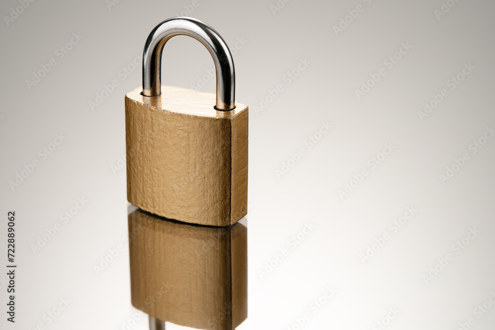 Poster single closed padlock in gold color on reflective surface. three-quarter front view.