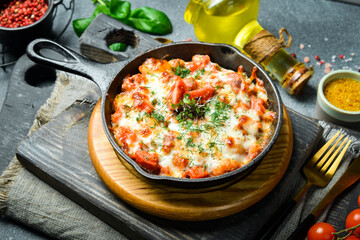 Vegetables baked with cheese in a pan. lasagna Hot appetizers. Restaurant serving. Close up. On a dark stone background.
