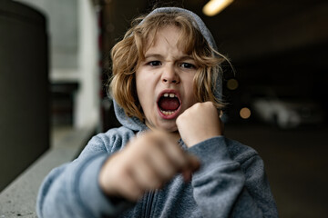Aggressive child. Aggression kid boy fighting on street. Angry aggression kid with fist. Aggression...