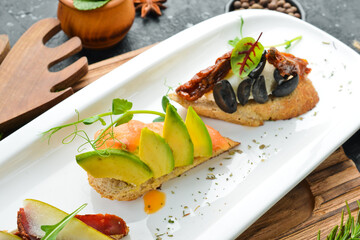 A set of bruschetta with avocado, tomatoes and meat. Antipasto Cold snacks. Restaurant menu. On a white plate.