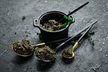Black caviar in a spoon. Macro photo of caviar. On a concrete background. Top view.