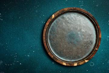 A dark stone plate on a blue stone table. Free copy space. Top view.