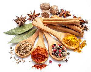 Colorful different seasonings in wooden spoons surrounded with herbs and spices on white background.