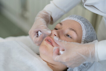 Professional evaluating the outcome of lip fillers, a beauty norm. It's a snapshot of the quest for...