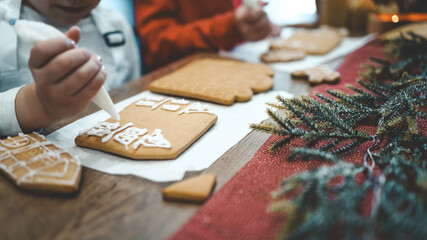 Children decorate gingerbread house, cozy homely Christmas atmosphere