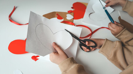 Child cuts out a postcard from paper, creativity for mom