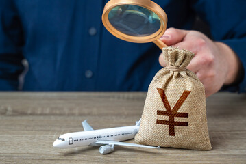 Airplane and chinese yuan or japanese yen money bag under investigation. Economic impact of...
