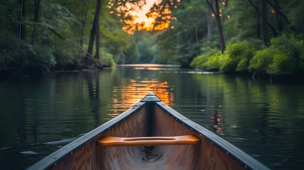 Foto op Canvas A canoe on a tranquil river, with lush forests on either side as the background, during a peaceful summer evening © CanvasPixelDreams