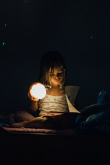 Un enfant lit un livre dans ca chambre le soir