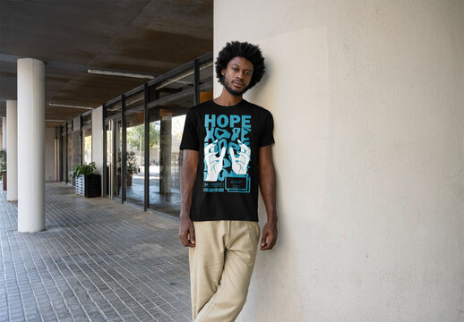 Mockup of man wearing customizable t-shirt by wall
