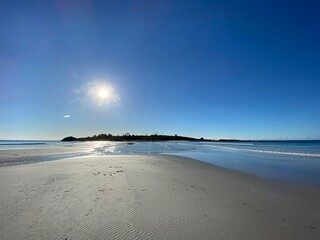 sun and island reflected in water on beach
