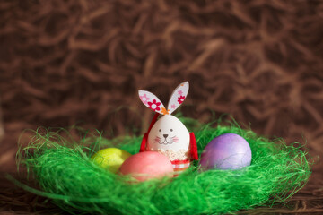 Colorful Easter eggs, green nest and bunny rabbit
