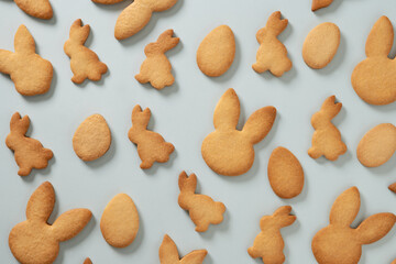 Easter cookies shaped of bunny on blue background. View from above. Festive food and kids snacks. Holiday Easter pattern.
