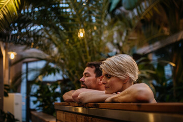 Beautiful mature couple relaxing in hot tub, enjoying romantic wellness weekend in spa. Concept of Valentine's Day.