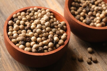 white pepper in the wooden bowl. pepper is a flowering vine in the family Piperaceae, cultivated for its fruit, which is usually dried and used as a spice and seasoning. Piper nigrum. 