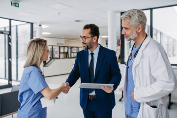 Pharmaceutical sales representative talking with doctors in medical building, presenting new...