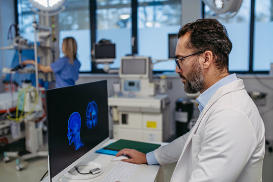 Portrait of ER doctor in hospital working in emergency room. Healthcare worker looking at MRI scan on medical computer in emergency room.