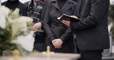 Bible, hands and family at funeral, cemetery or burial ceremony religion by coffin tomb. Holy book,...