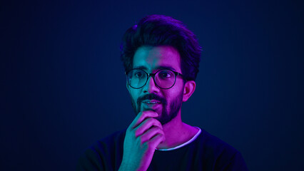 Close up male portrait in neon studio ultraviolet background blue backdrop Arabian Muslim shocked...