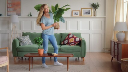 young blonde woman enter living room carrying green plants, put the on furnished for coziness and home staging, sits down to enjoy and rest