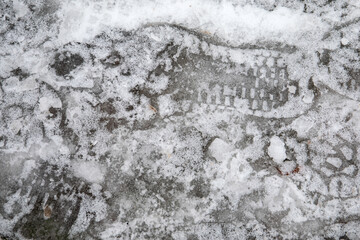 Frozen water on the sidewalk, footprints in the ice