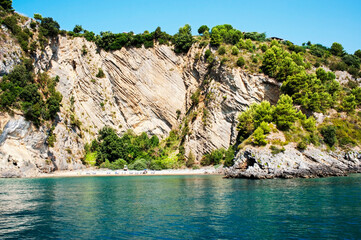Fascinating narrow sandy beach at the bottom of the arched cliffside. Palinuro coast, Salerno, Italy. 