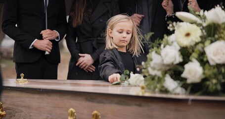 Death, grief and girl at funeral with flower on coffin, family and sad child at service in...