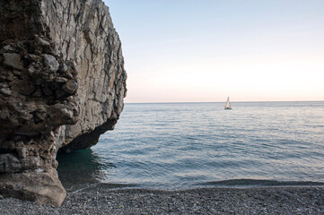 Afterglow of the sunset over the cove with the shingle beach and sea cliff. Marina di Camerota, Italy.