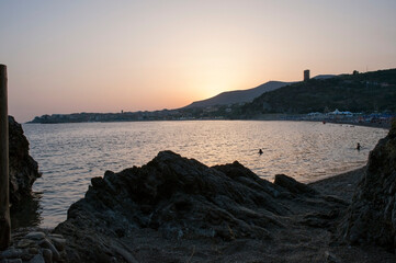 Last glows of sunset over the bay with people still on the beach. Marina di Camerota, Salerno, Italy.