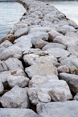 Mass of aligned boulders to dam the water. Breakwater.