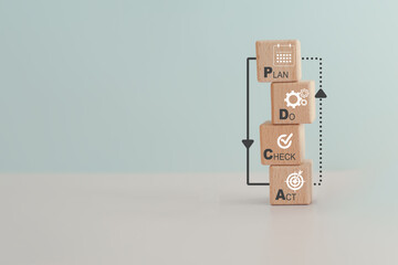 PDCA text,means Plan Do Check Act, and icon on wooden cube blocks with loop line including copy...