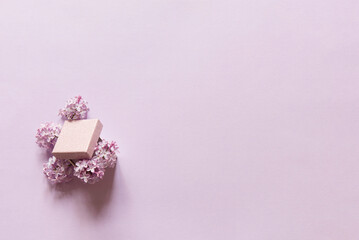 Gift box and lilac flowers on a lilac plain background. Beautiful flowers composition. Valentines Day, Easter, Birthday, Happy Women's Day, Mother's day. Flat lay, copy space, top view