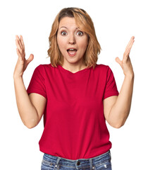 Blonde middle-aged Caucasian woman in studio celebrating a victory or success, he is surprised and...