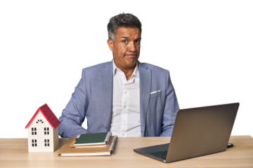 Middle-aged Hispanic businessman with real estate theme confused, feels doubtful and unsure.