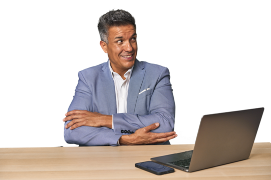 Elegant businessman at desk with laptop smiling confident with crossed arms.