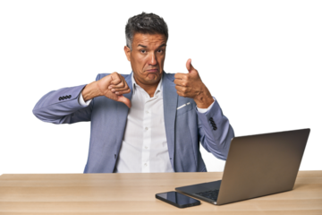 Elegant businessman at desk with laptop showing thumbs up and thumbs down, difficult choose concept