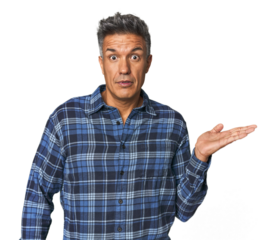 Middle-aged Latino man impressed holding copy space on palm.