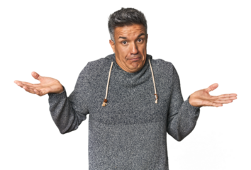 Middle-aged Latino man doubting and shrugging shoulders in questioning gesture.