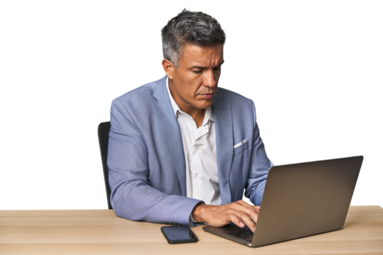 Middle-aged Hispanic man working on laptop in business suit
