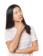 Young Chinese woman in studio setting looking sideways with doubtful and skeptical expression.