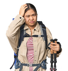 Young Chinese woman with hiking gear ready for adventure being shocked, she has remembered...