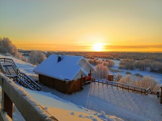 Old wooden house in Arkhangelsk under the snow at sunset.