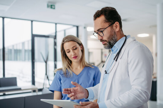 Doctor and nurse looking at test results on tablet, talking about patients diagnosis.