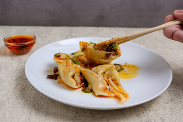 Chili Oil Wontons are a Chinese dumpling dish often served in soup or fried. Wonton filling usually consists of a mixture of minced meat (such as chicken or shrimp) and spices.